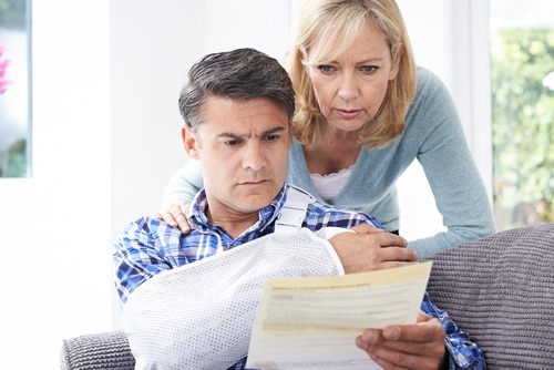 couple reviewing a medical bill - there are "damage caps" on how u=much injury victims can collect in Colorado